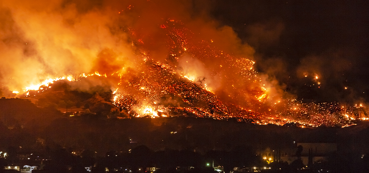 Fire burning across hills at night